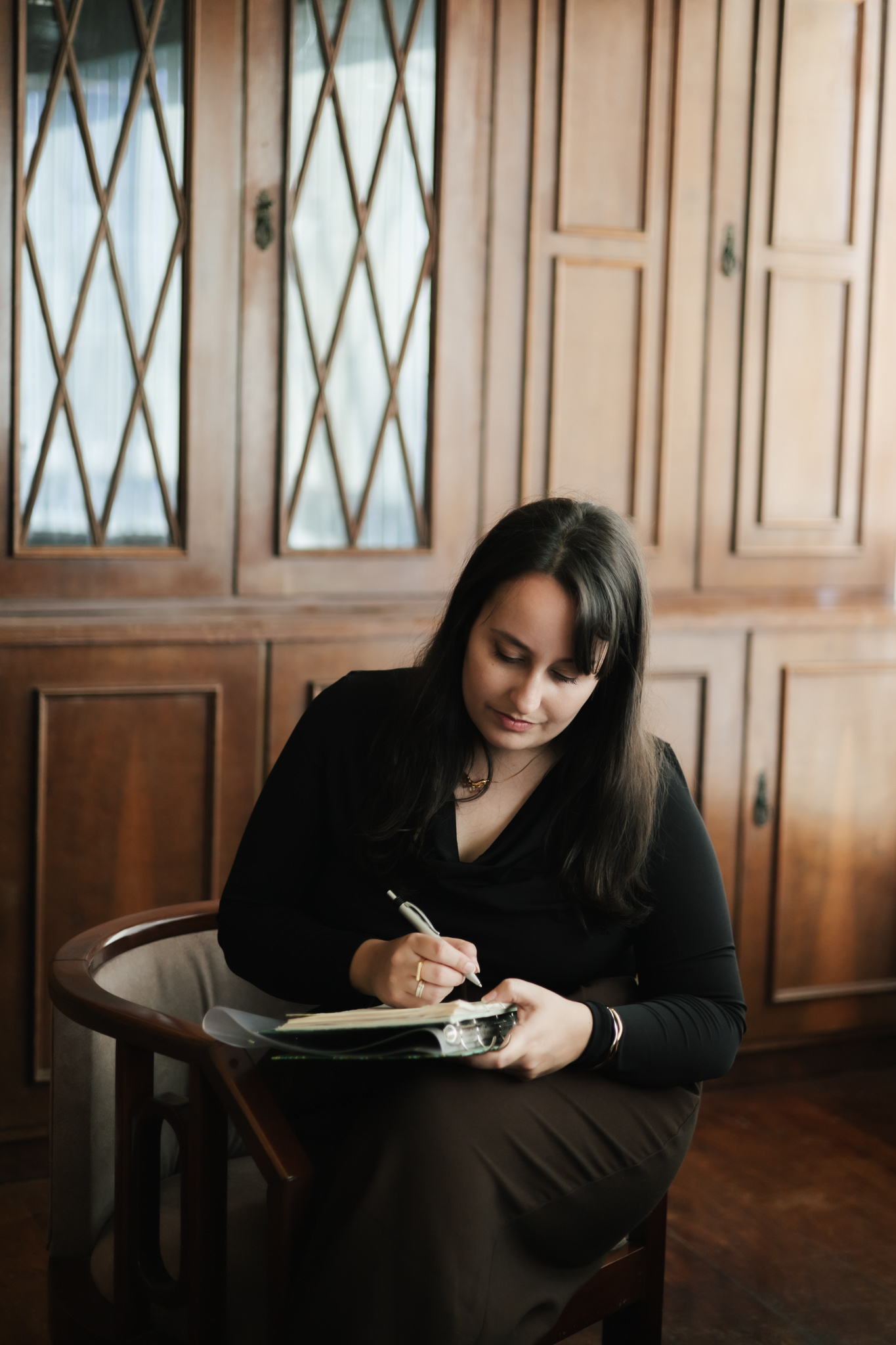 Amanda sentada no consultório, fazendo anotações em um caderno