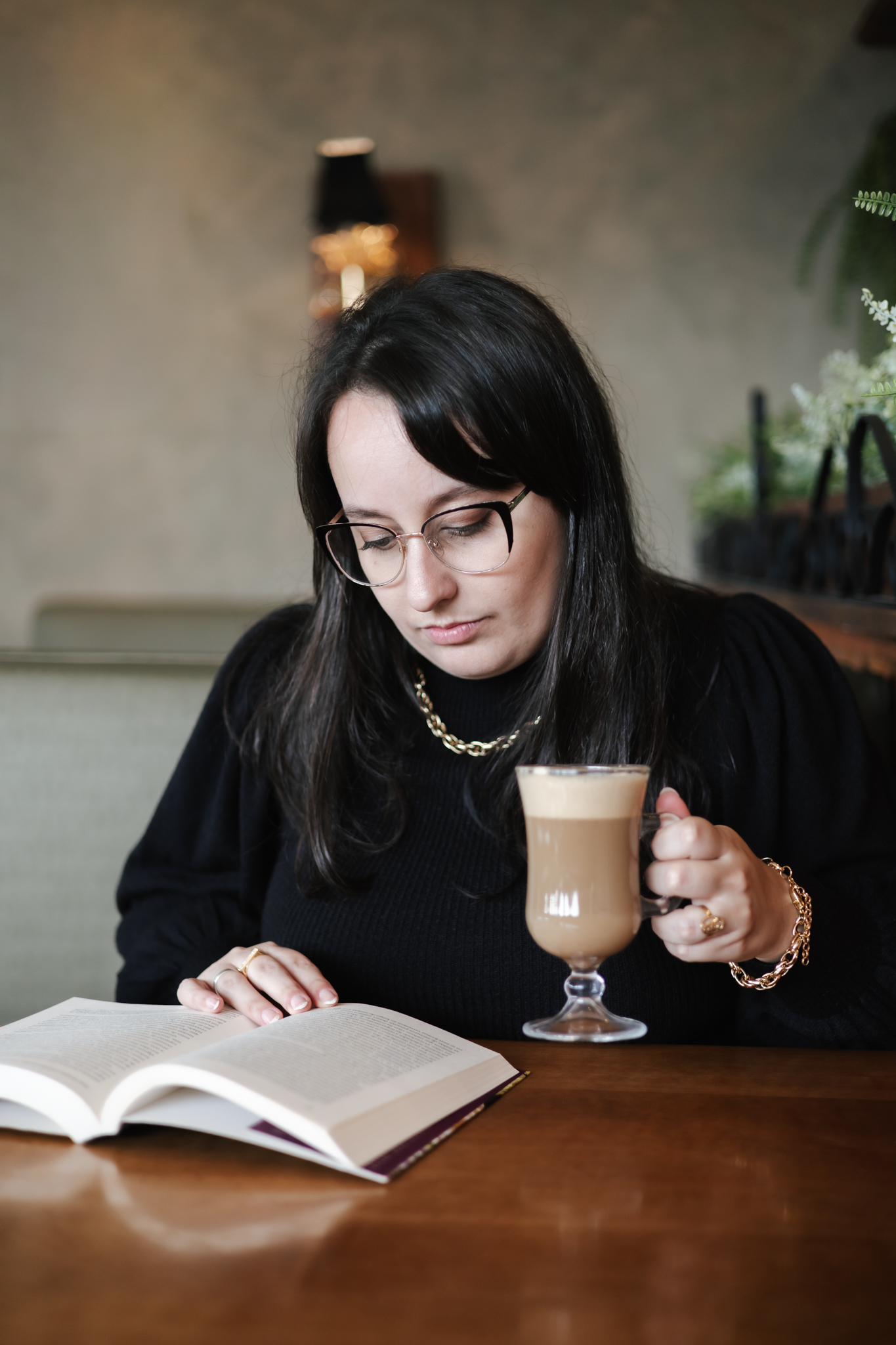 Amanda lendo um livro com uma xícara de café nas mãos